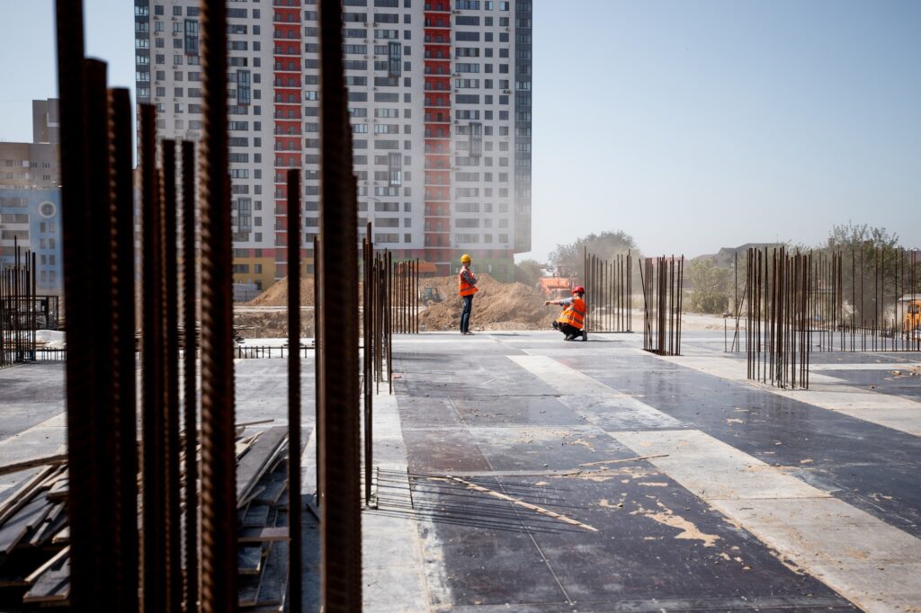The building site against the background of a multistorey building. Two builders are working
